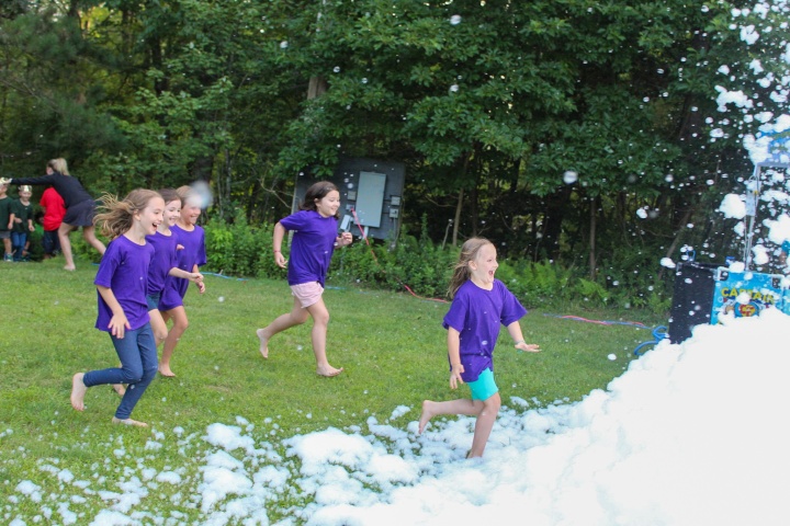 a group of girls running towards a pile of soap bubbles
