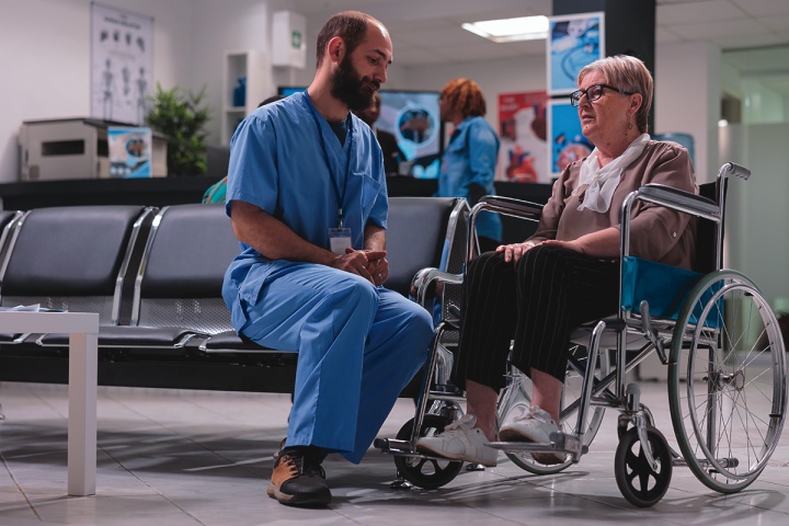 A doctor talking with a patient in a wheelchair. 