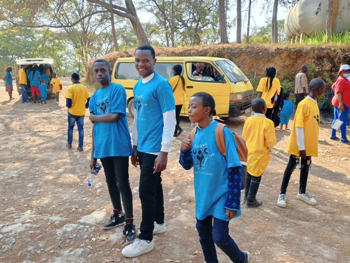 a group of children and teenagers standing outside in front of a bus