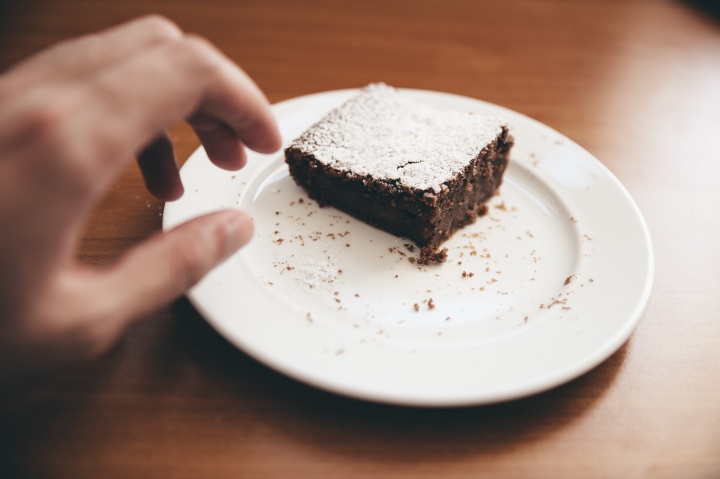 a hand reaching for a brownie on a plate