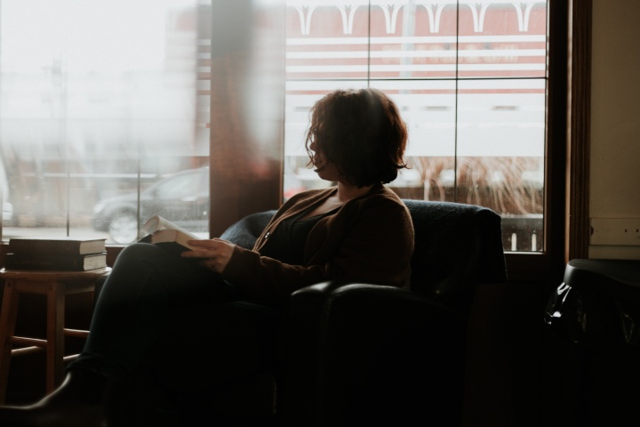 A woman sitting in a chair looking at a book.