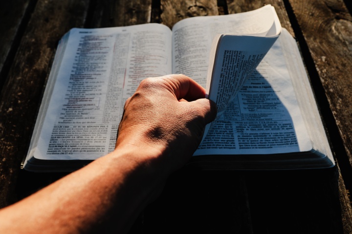 A man turning pages of a Bible.