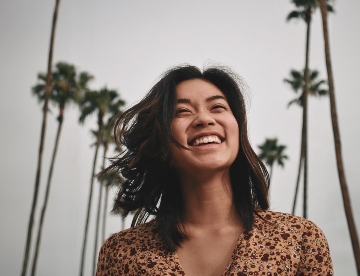 a smiling woman with palm trees in the background