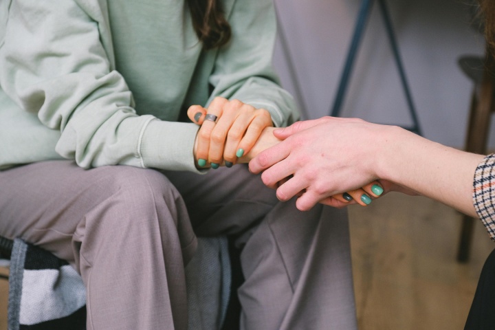 a woman extending a hand to another woman, sitting across from her