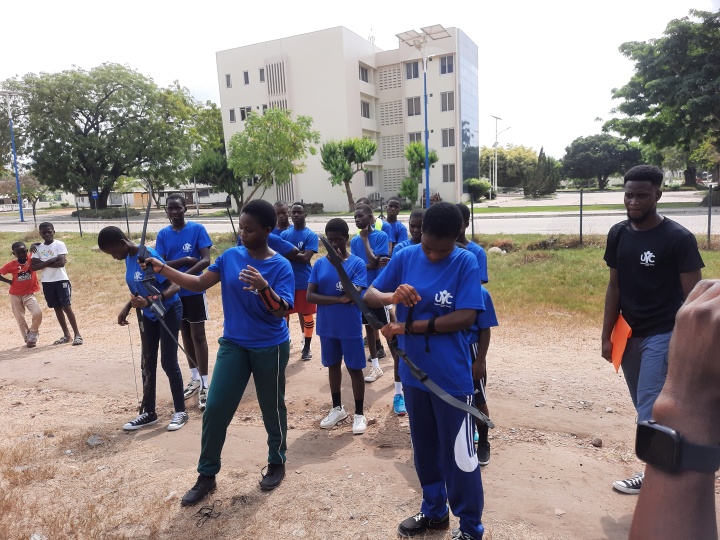 a group of teenagers with archery equipment outdoors