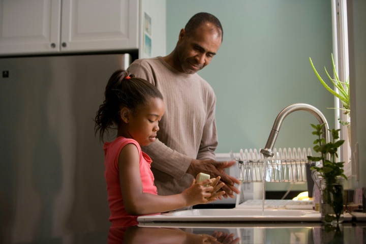 a father and daughter washing hands together in the kitchen