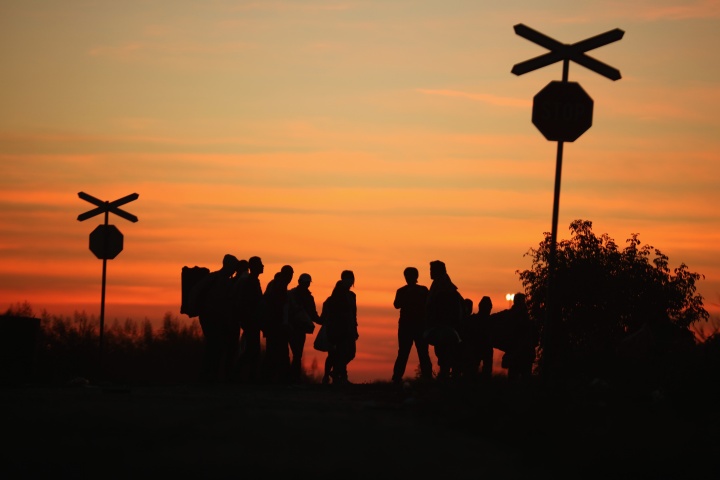 Silhouette of people standing at a railroad creossing.