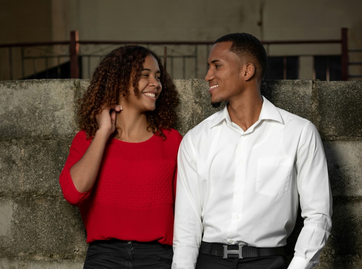 a man and woman standing against a stone wall