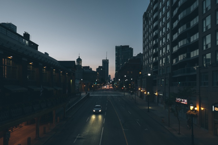 A car driving down a dark street in a big city.