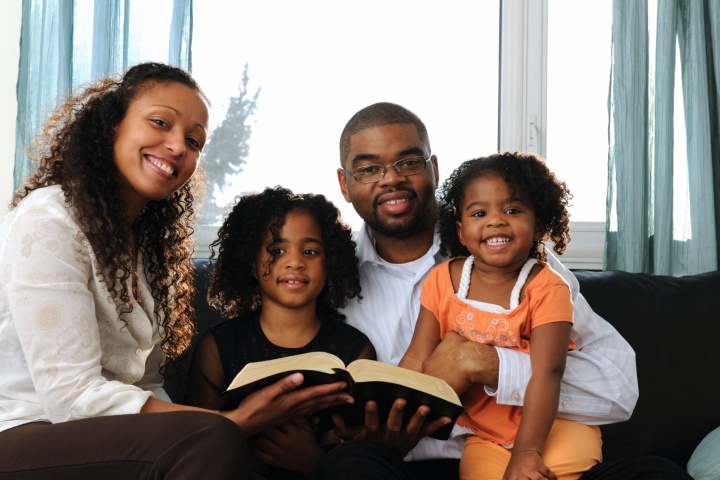 A young family reading Bible to children.