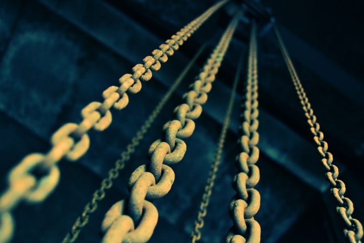 Old chains hanging down from a dark ceiling.