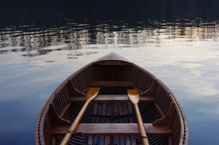 An empty wooden boat with two wooden oars.
