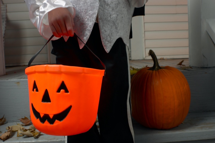 A child carry a jack-o-lantern bucket for candy.
