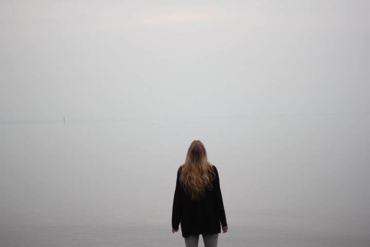 A woman standing by herself looking up.