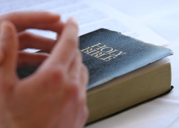 Hand on top of a Holy Bible.