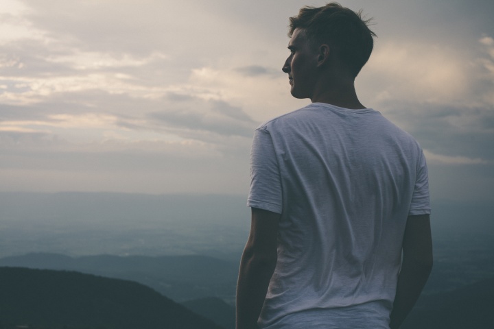 A young man looking over the vista of a mountain.