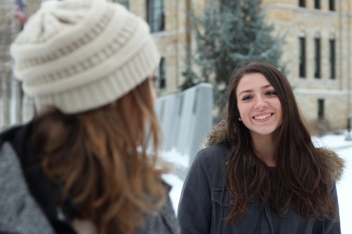 Two young adult women talking to each other while being outside in the cold.