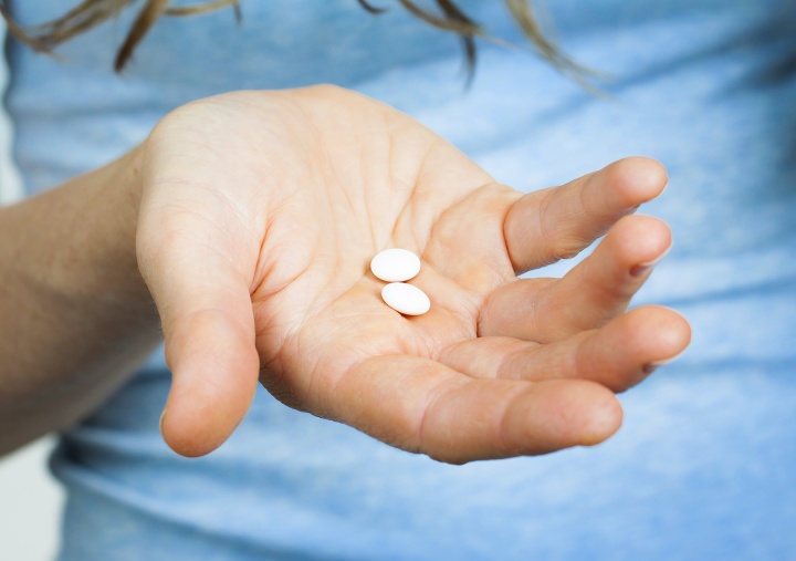 A woman holding pills in palm of hand.