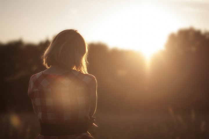 A girl sitting outside looking at sunset.