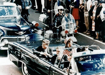 President John F. Kennedy  riding in a motorcade in Dallas, Texas.