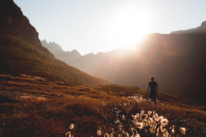 A person walking on a path up to a mountain peak.