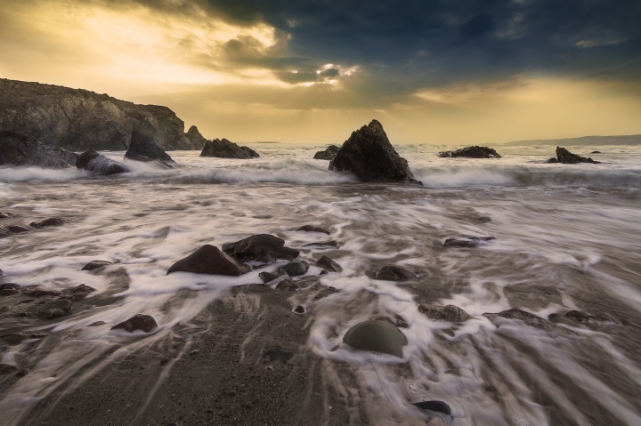 Sunset over the ocean - waves crashing into shore.