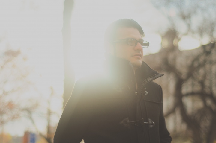 A young man walking with sun rays behind him.