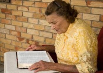 Older woman reading bible on a table - Understanding God's Word... What Is the G