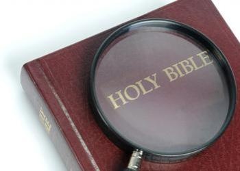 Magnifying glass over the words Holy Bible.