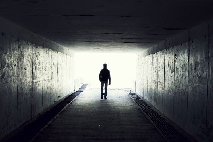 A man walking in a dark tunnel.