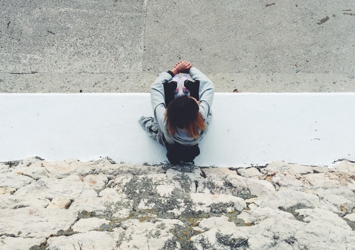 A woman sitting on a sidewalk.