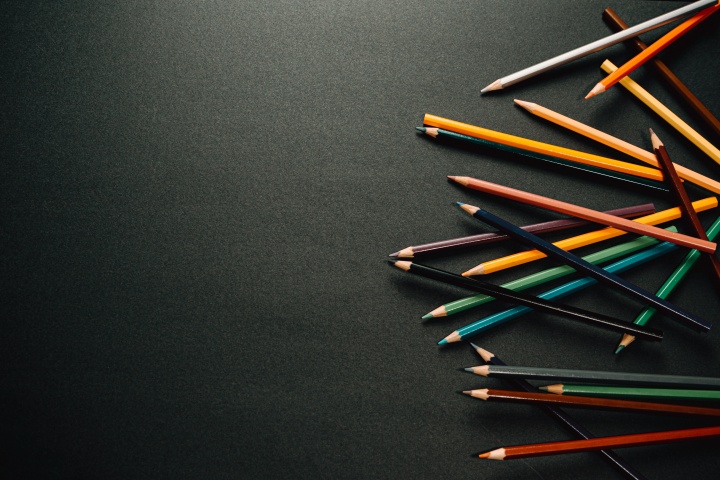 scattered colored pencils along the right edge of a dark background