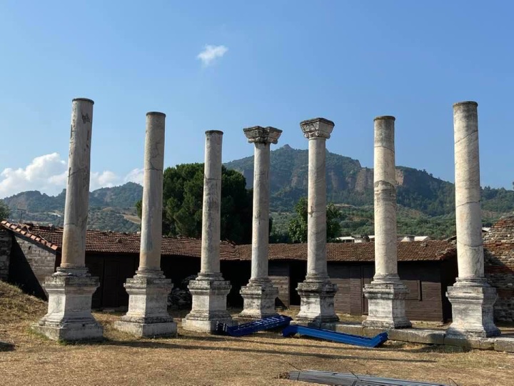 Pillars still stand at the site of the ancient city of Sardis.  Behind them, the famous acropolis rises into the sky.