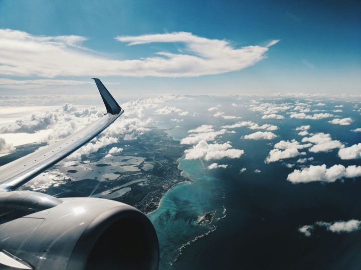 an airplane over a cloudy sky with water below