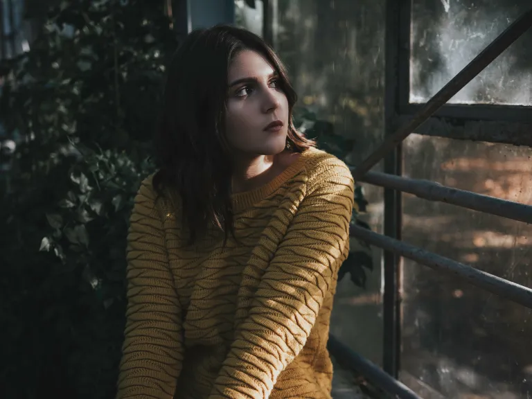 The more we submit to God and ask for His help in seeing what we need to change, the more He opens our minds to recognize our faults and weaknesses. A young woman looking out a window.