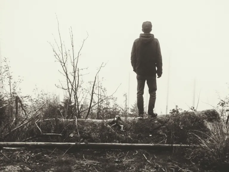 A young man walking in a foggy forest.