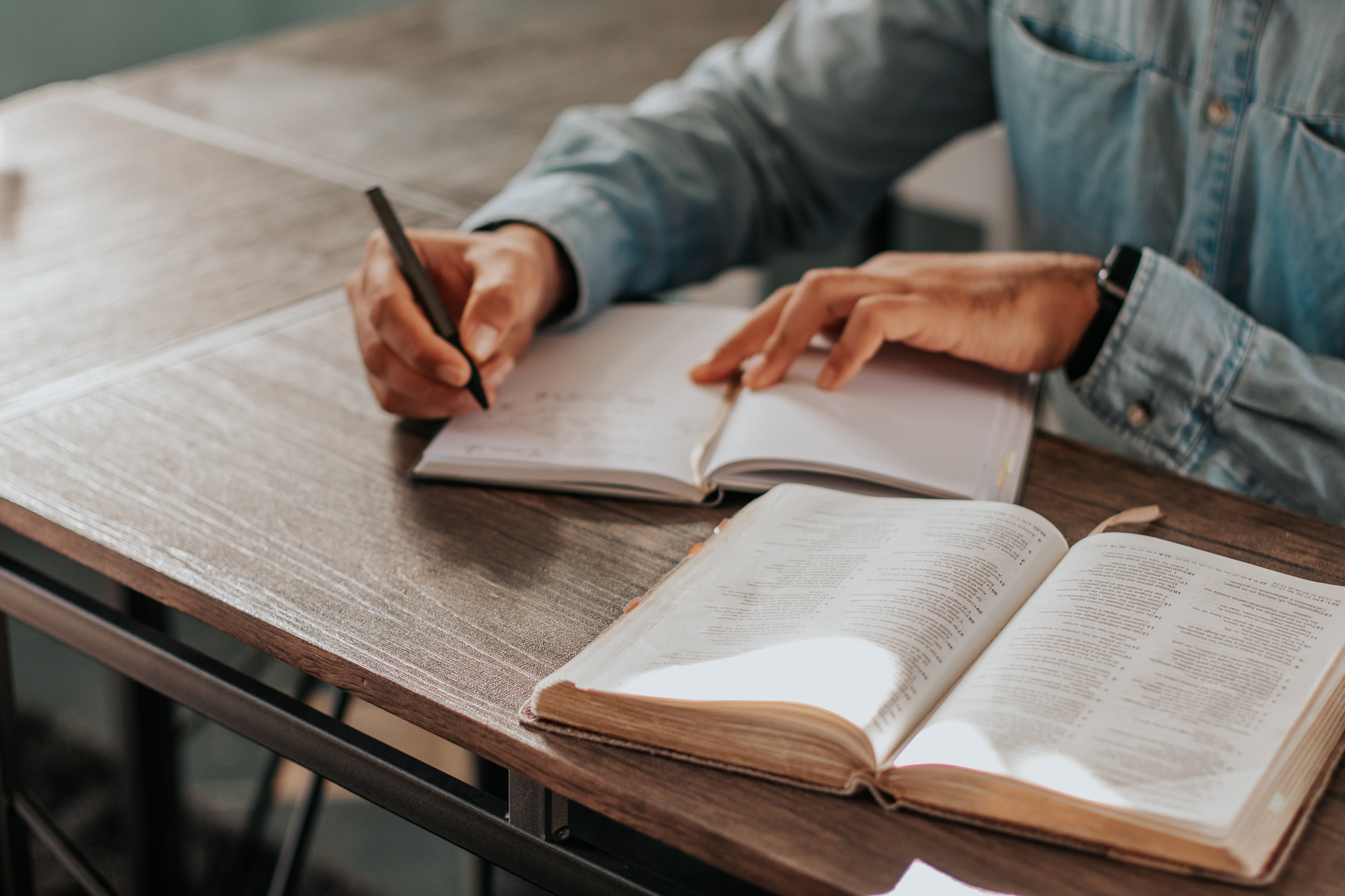 A person taking notes with a Bible opened.